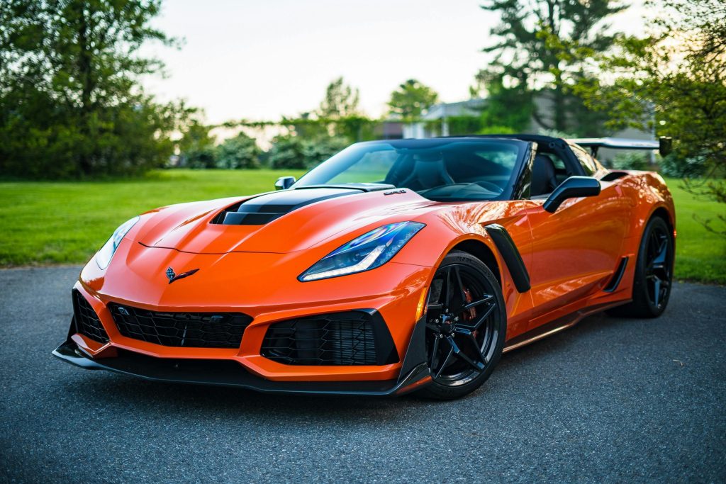 A sleek orange convertible sports car elegantly parked on a scenic outdoor road.